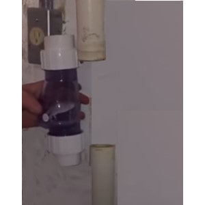 Step Six: The images shows the home ower confirming the length of the check favle by placing it next the the discharge pipe. If the dishrage pipe is too long cut the pipe off. If the PVC pipe is too short add more PVC.